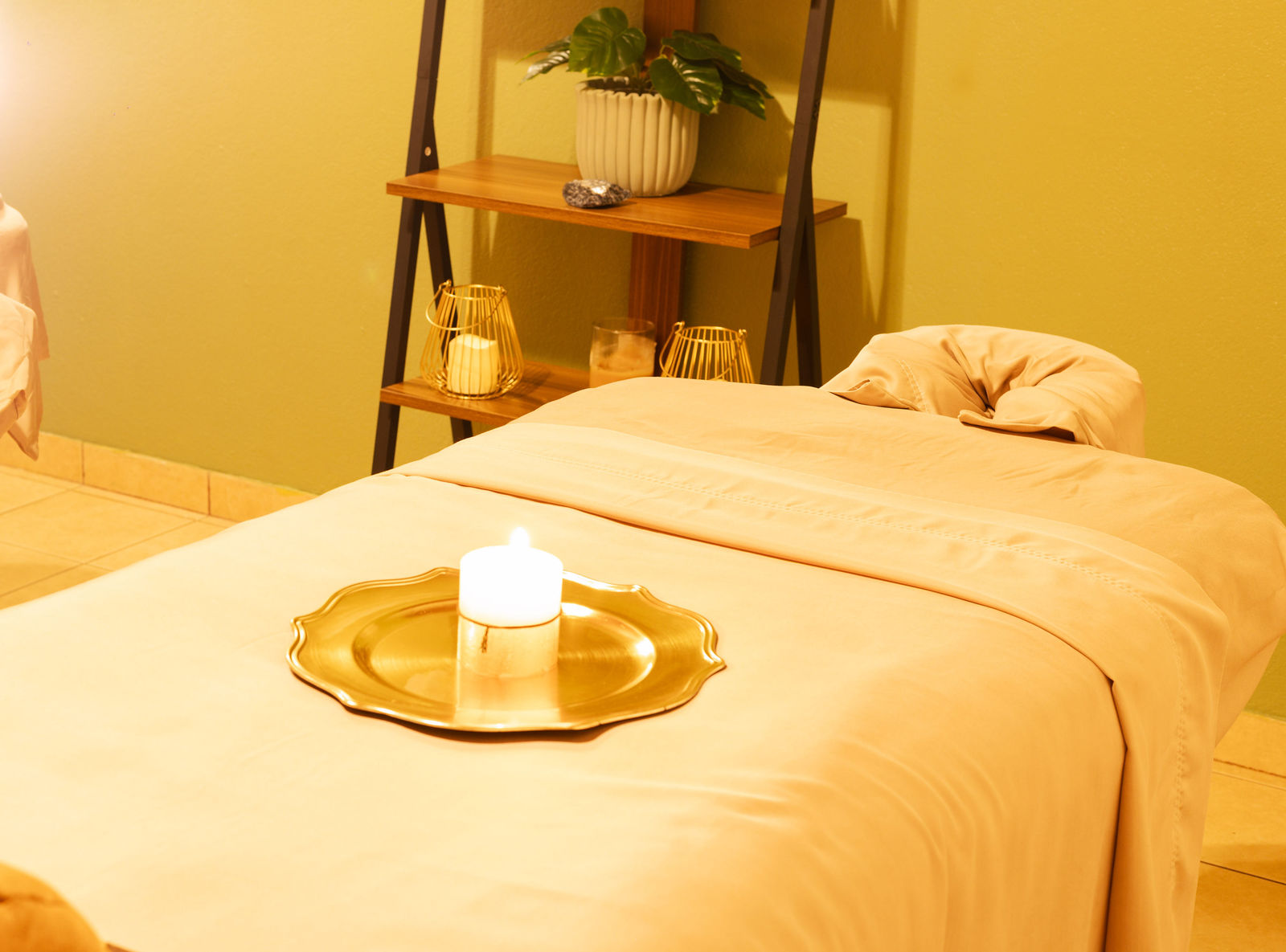 Massage table with a lit candle on a gold plate