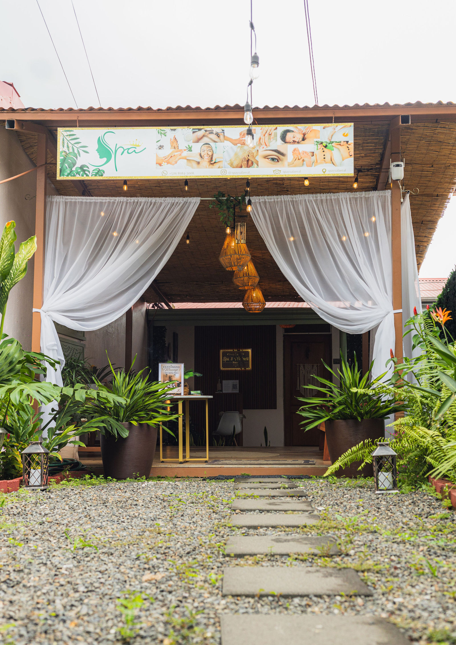 Spa entrance with white drapes and a tropical garden